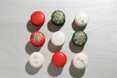 Different decorated Christmas macarons on wooden table, flat lay