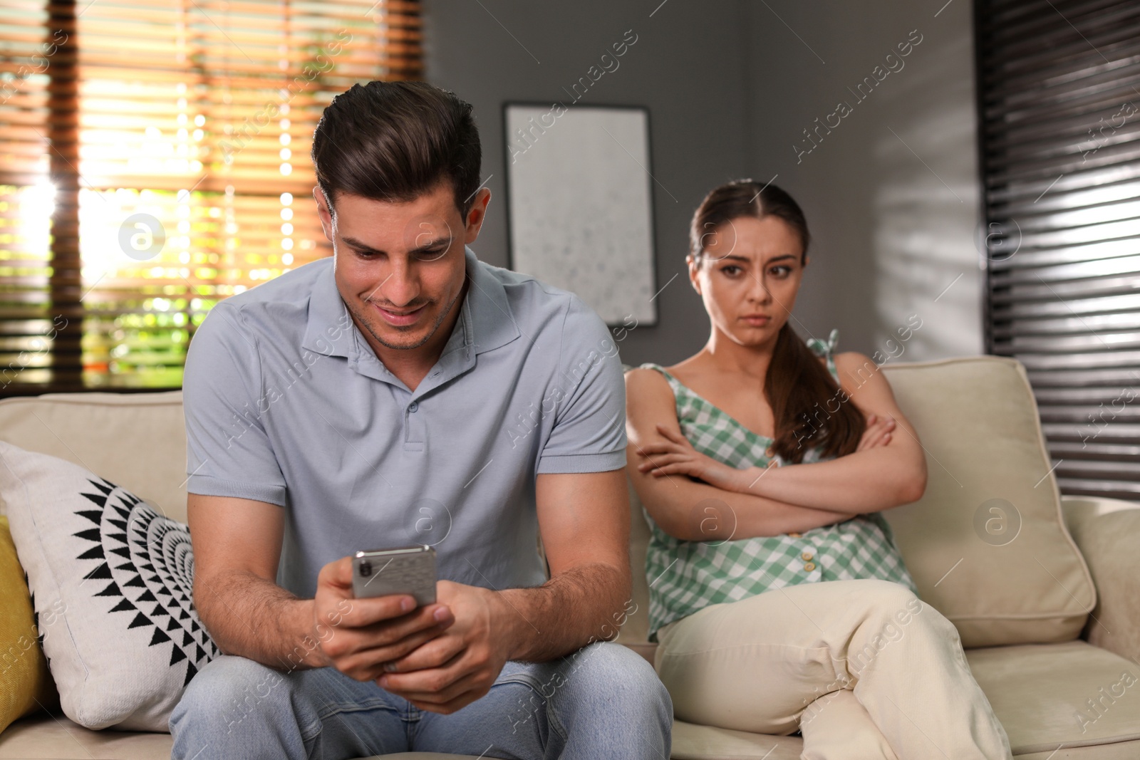 Photo of Man preferring smartphone over spending time with his girlfriend at home. Jealousy in relationship