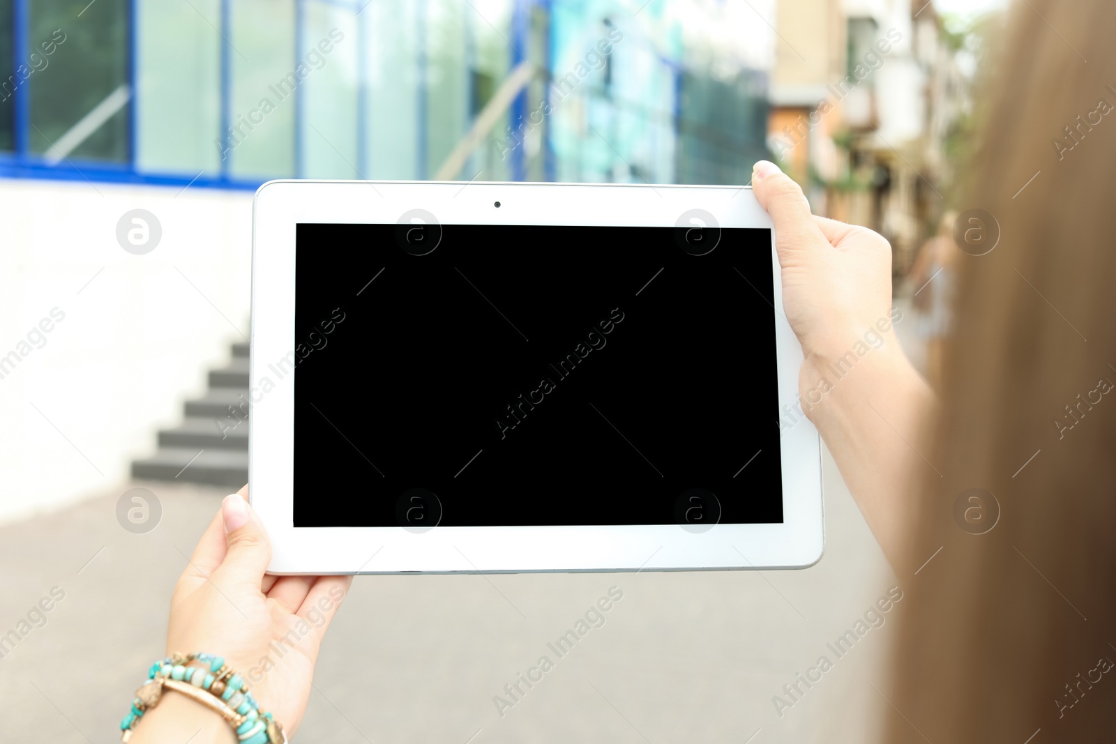 Photo of Woman holding tablet with blank screen outdoors. Mockup for design