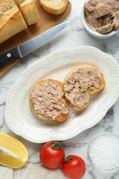 Photo of Tasty sandwiches with cod liver on white marble table, flat lay