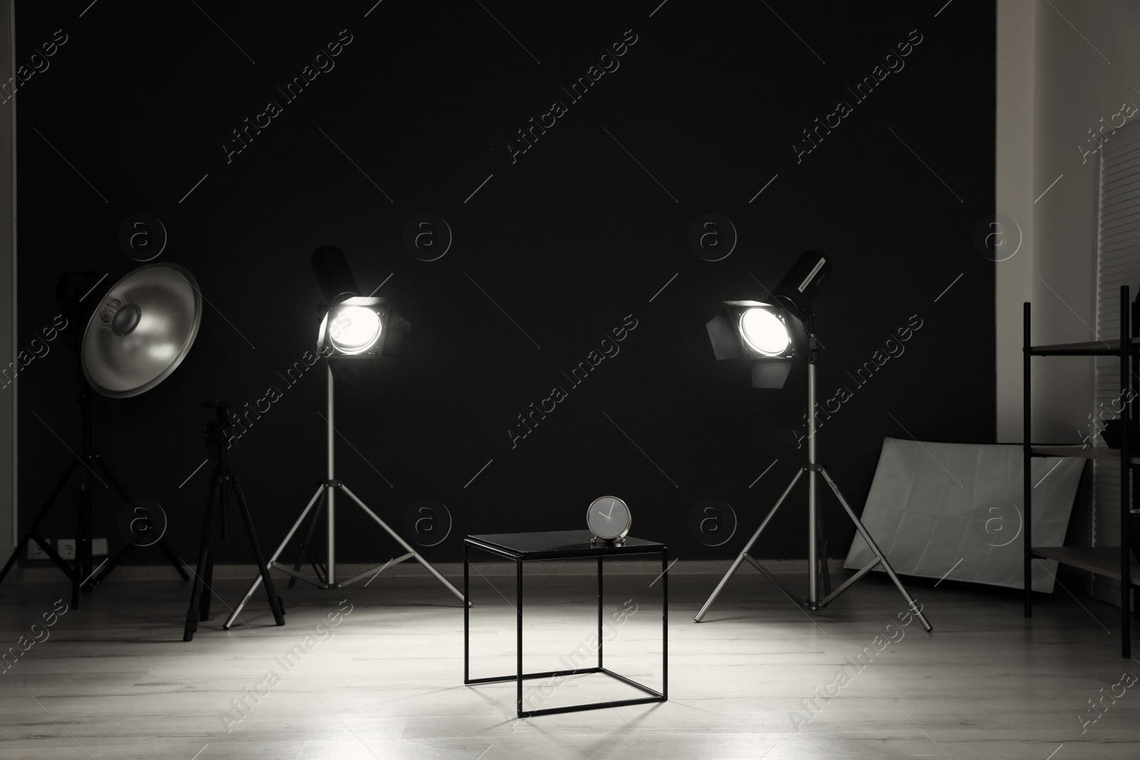 Photo of Interior of modern photo studio with table, clock and professional equipment