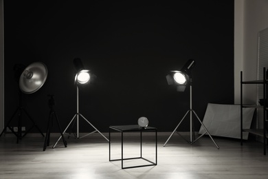 Photo of Interior of modern photo studio with table, clock and professional equipment