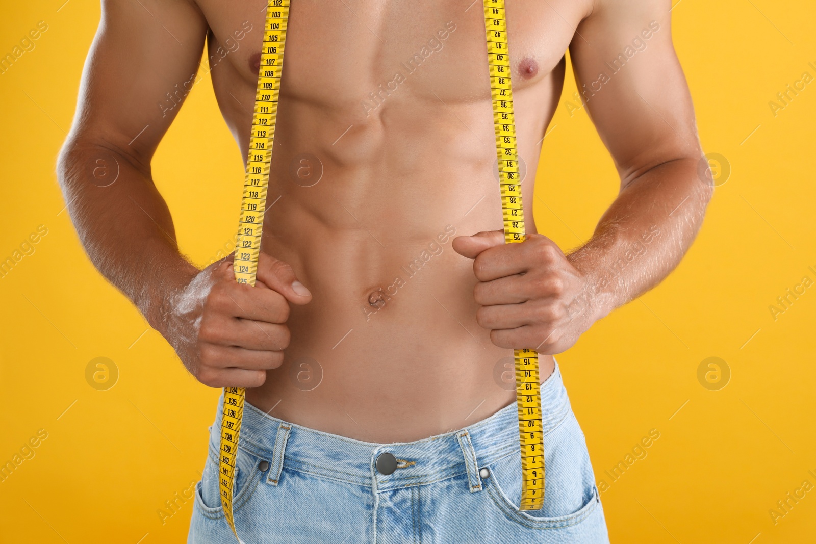 Photo of Shirtless man with slim body and measuring tape on yellow background, closeup