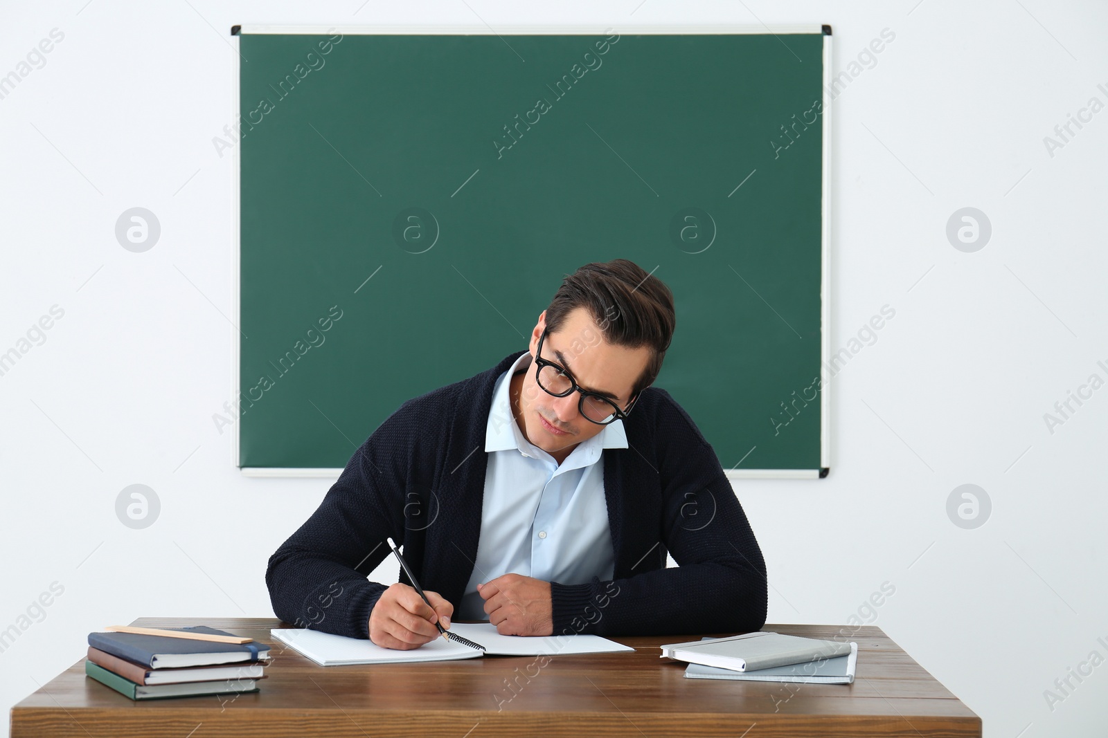 Photo of Young teacher working at table in classroom