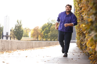 Photo of Young overweight man running in park. Fitness lifestyle