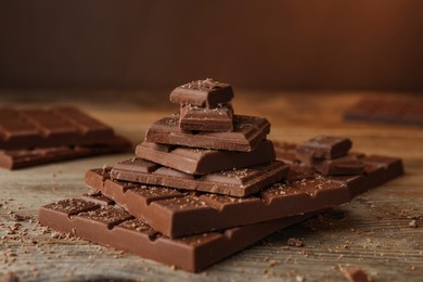 Photo of Pieces and crumbs of tasty chocolate on wooden table, closeup