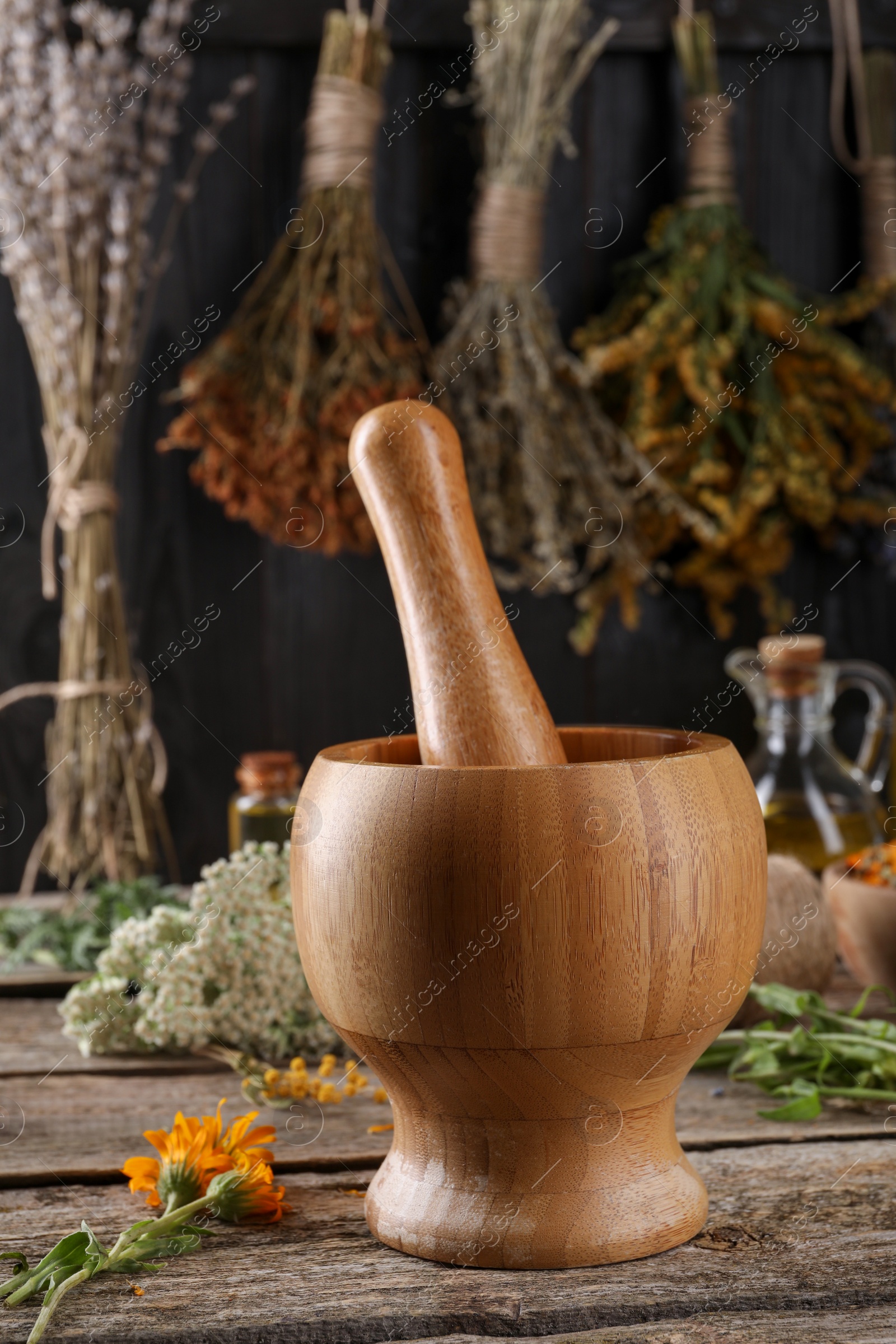 Photo of Mortar with pestle and calendula flowers on wooden table. Medicinal herbs