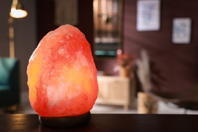 Himalayan salt lamp on wooden table indoors, space for text