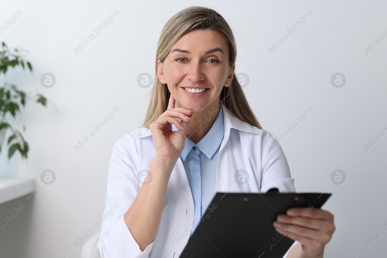 Photo of Portrait of happy doctor with clipboard in hospital