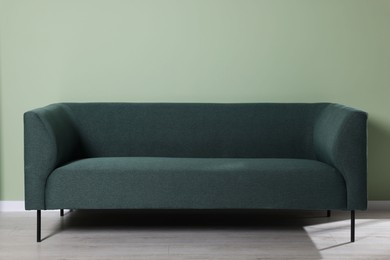 Photo of Comfortable sofa near light green wall indoors