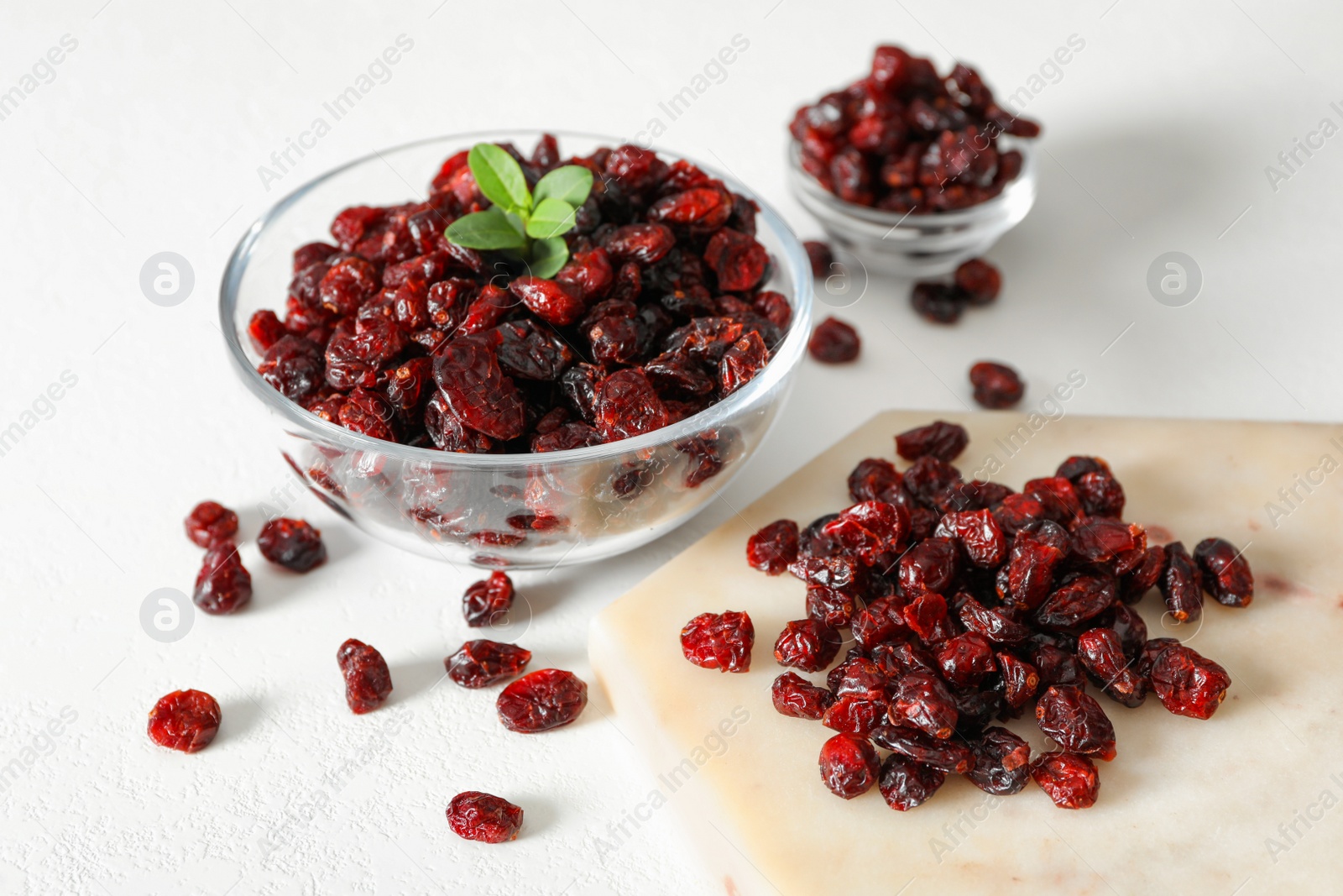 Photo of Tasty dried cranberries and leaves on white table