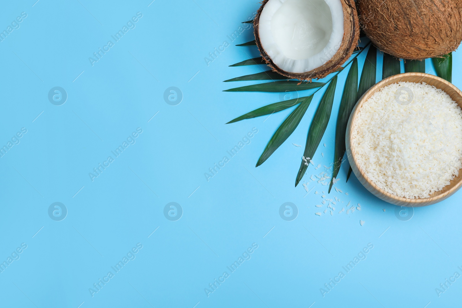 Photo of Flat lay composition with fresh coconut flakes on light blue background. Space for text