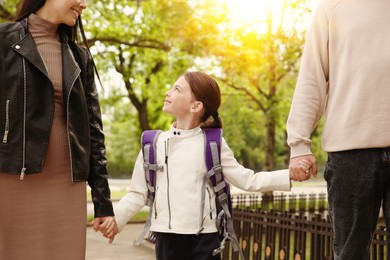 Parents taking their little daughter to school outdoors