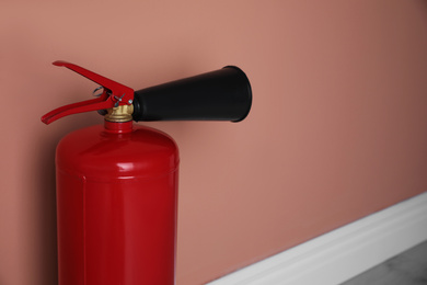 Fire extinguisher near color wall indoors, closeup. Space for text