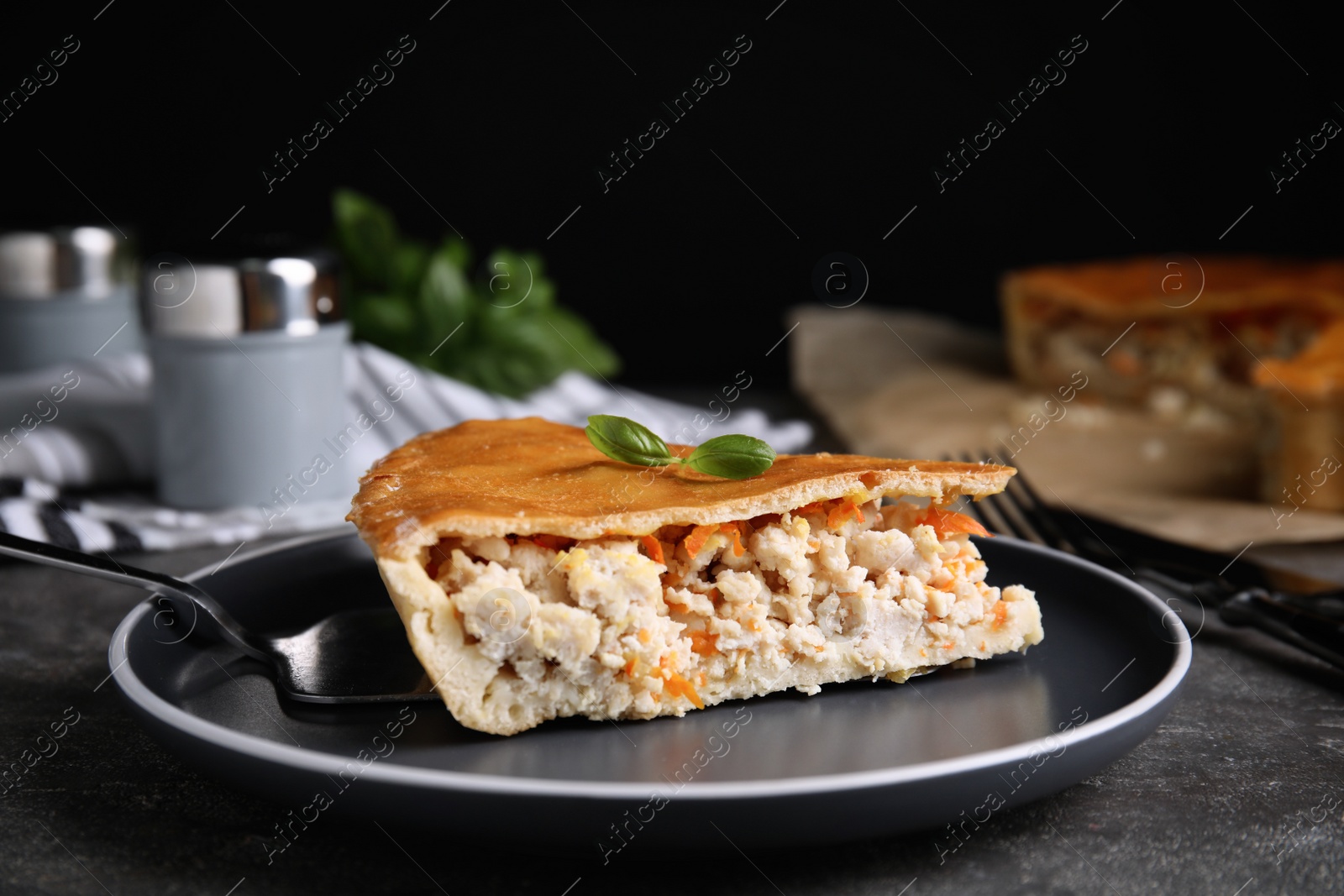 Photo of Piece of delicious pie with meat and basil on grey table