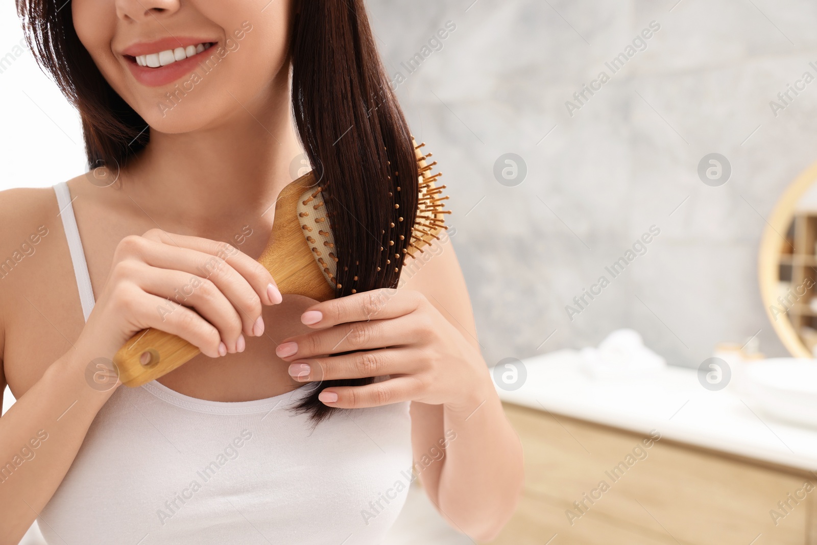 Photo of Woman brushing her hair in bathroom, closeup. Space for text