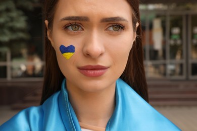 Photo of Young woman with Ukrainian flag outdoors, closeup