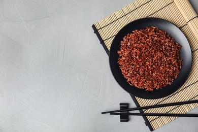 Photo of Flat lay composition with delicious cooked brown rice on grey table. Space for text