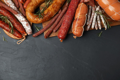 Photo of Different tasty sausages on black table, flat lay. Space for text