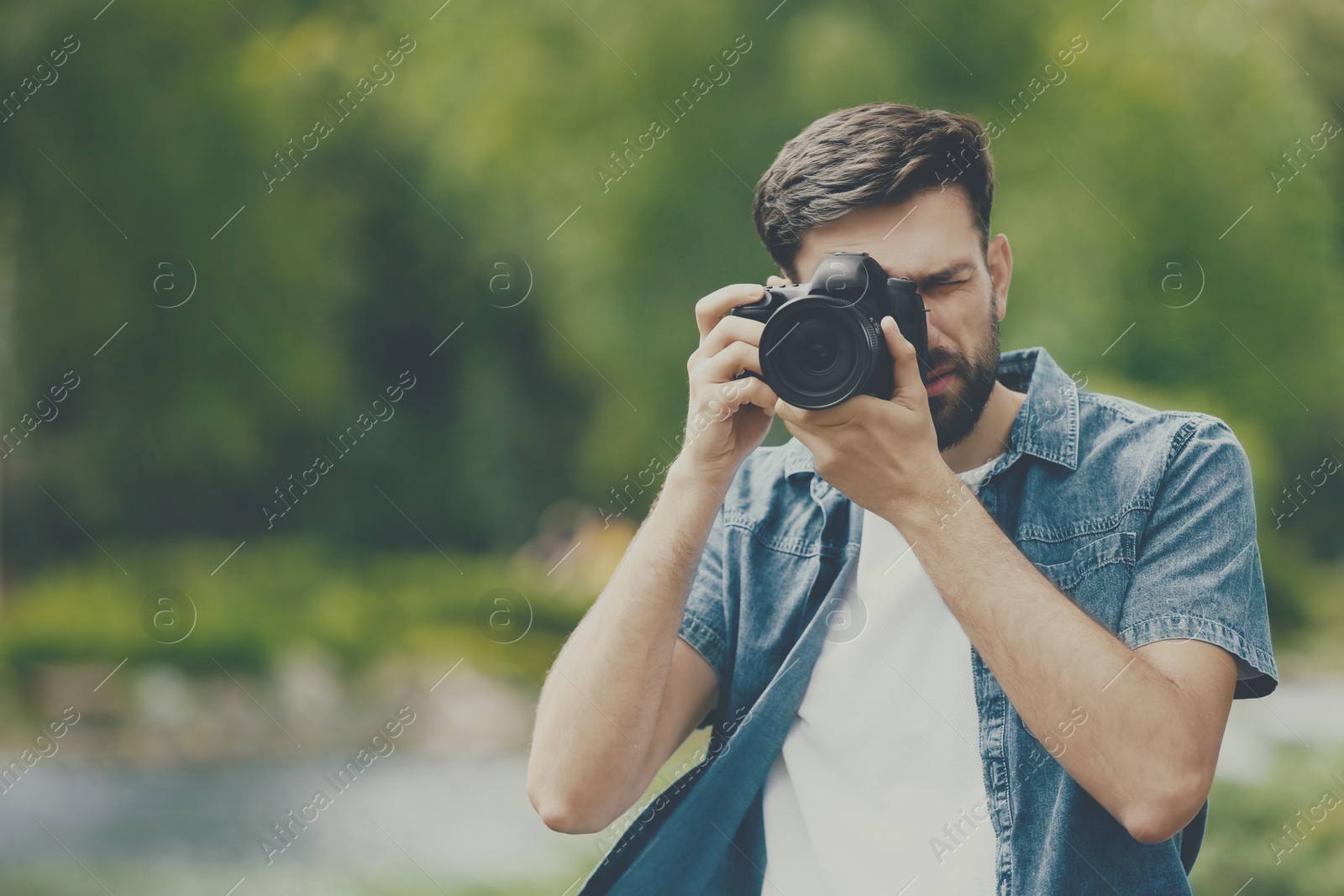 Image of Photographer taking photo with professional camera in park