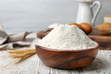 Photo of Bowl with flour on wooden table