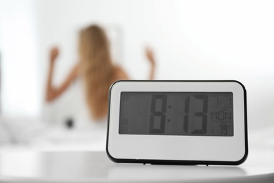 Photo of Digital alarm clock and blurred woman on background. Time of day