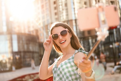 Photo of Beautiful young woman with sunglasses taking selfie outdoors