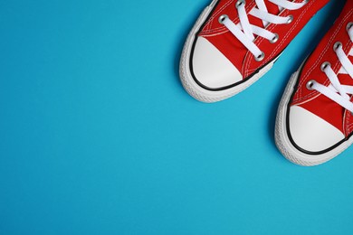 Photo of Pair of new stylish red sneakers on light blue background, flat lay. Space for text