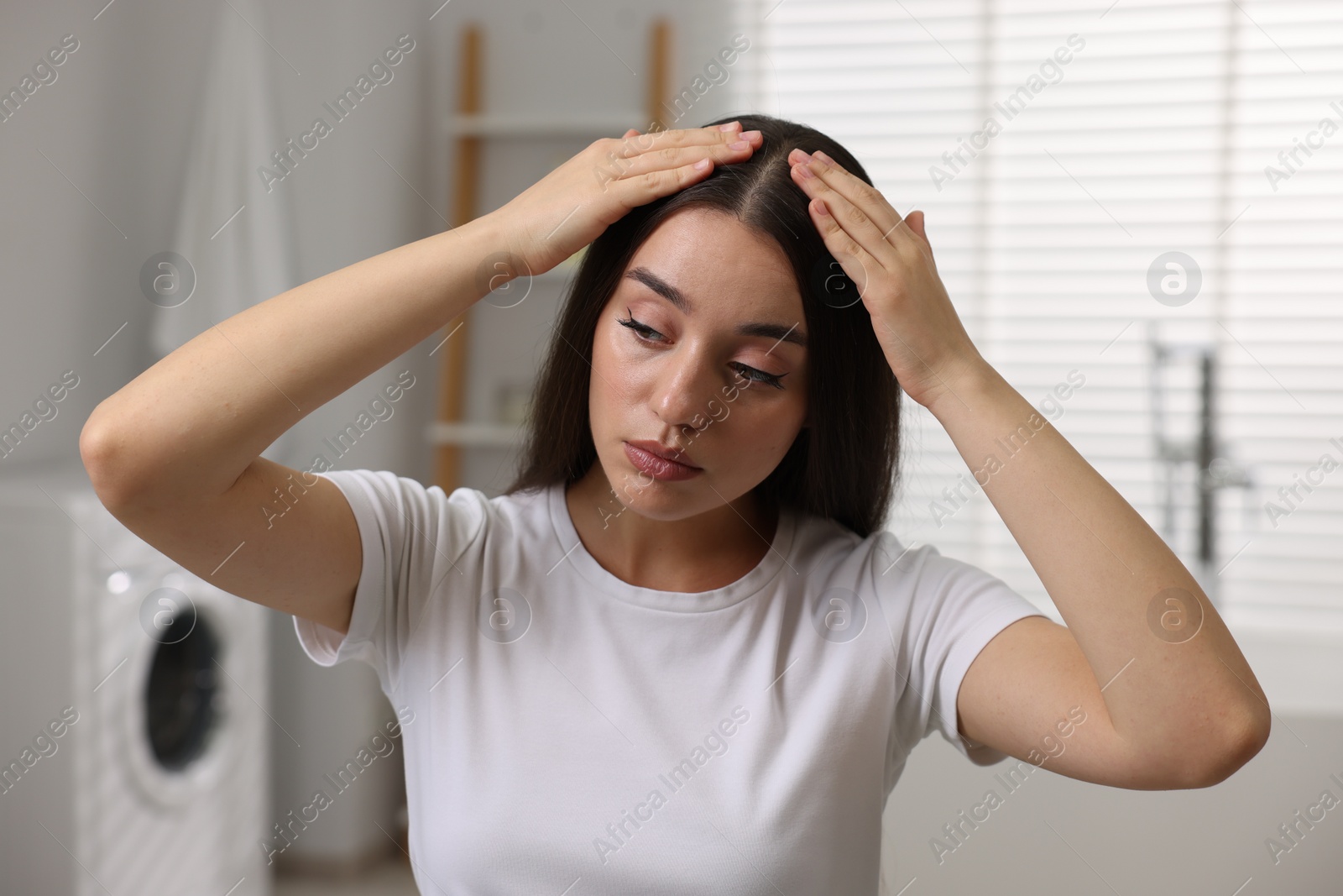 Photo of Woman examining her hair and scalp in bathroom