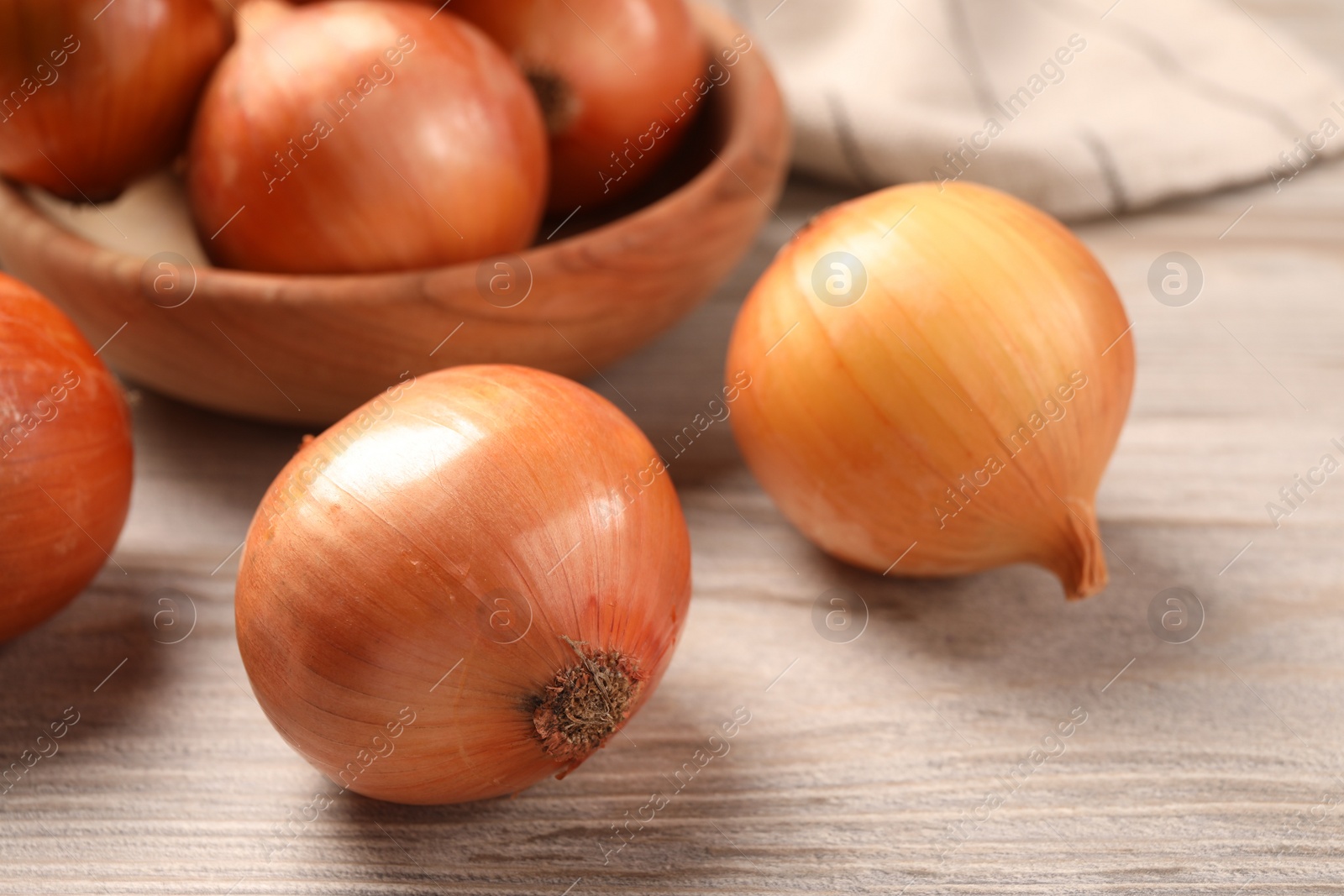 Photo of Many ripe onions on wooden table, closeup