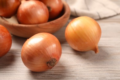 Many ripe onions on wooden table, closeup