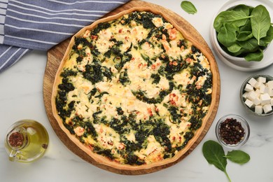 Photo of Delicious homemade spinach quiche and ingredients on white table, flat lay