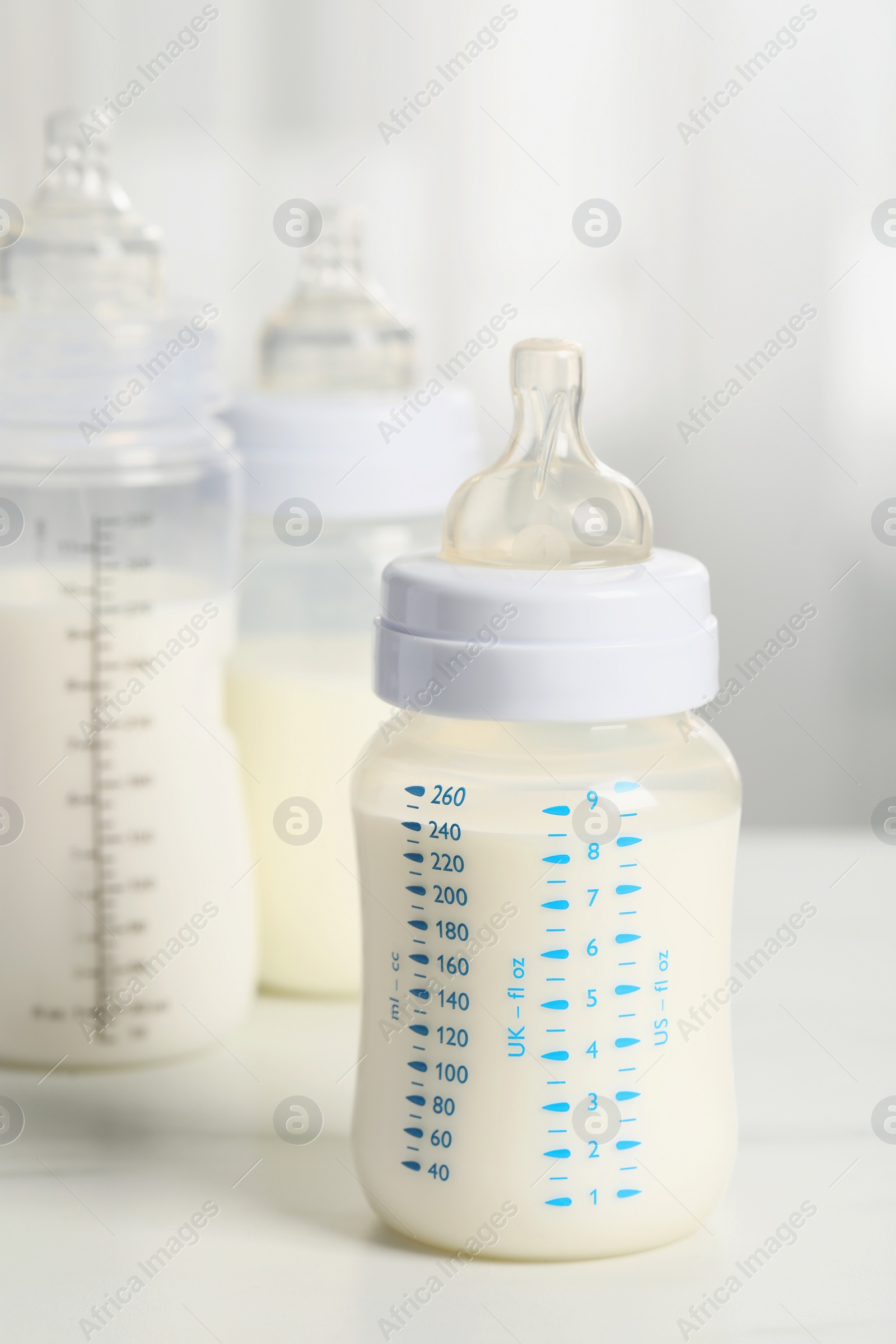 Photo of Feeding bottles with milk on white table indoors