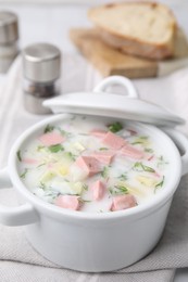 Photo of Delicious cold summer soup (okroshka) with boiled sausage in pot on table