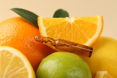 Skincare ampoule with vitamin C, different citrus fruits and leaves on beige background, closeup