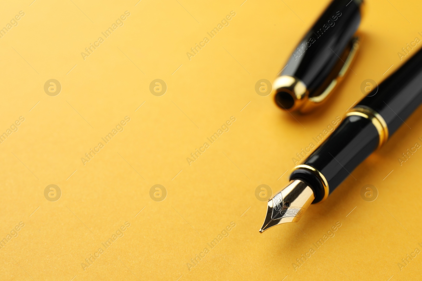 Photo of Stylish fountain pen with cap on yellow background, closeup. Space for text