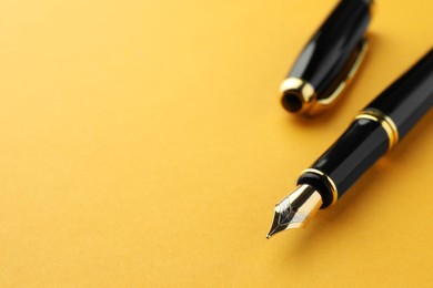 Photo of Stylish fountain pen with cap on yellow background, closeup. Space for text