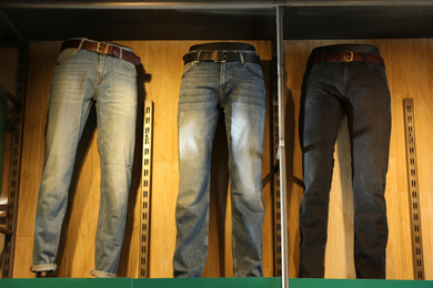 Different stylish jeans on mannequins in shop