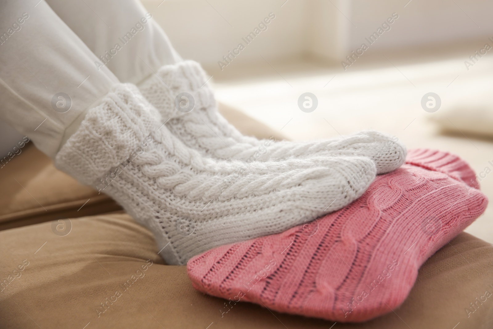 Photo of Person warming feet with hot water bottle on sofa, closeup