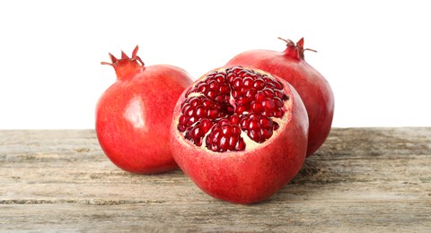 Photo of Fresh pomegranates on wooden table against white background