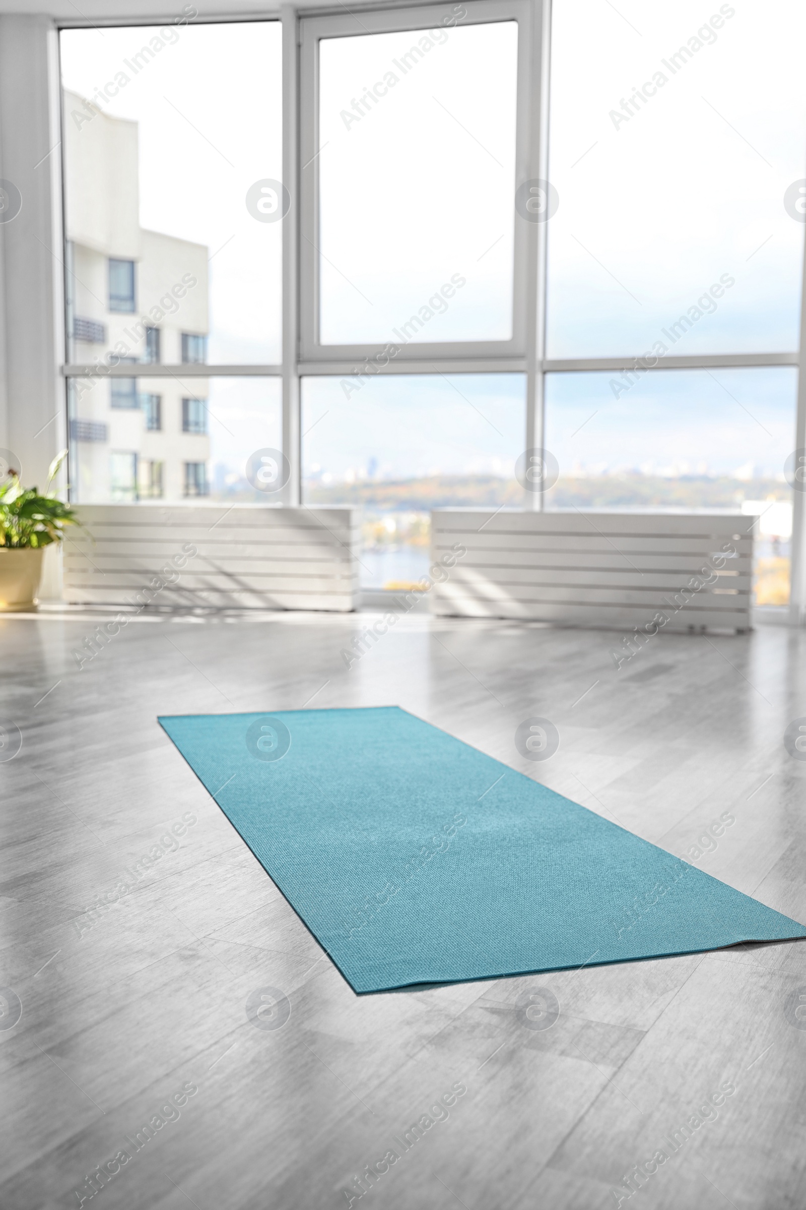 Photo of Unrolled light blue yoga mat on floor in room