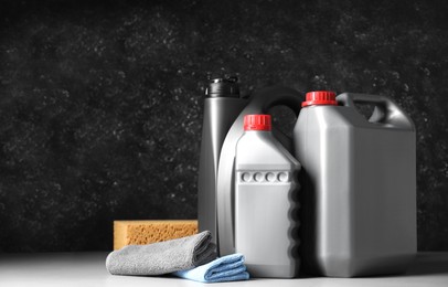 Photo of Car cleaning products, canisters with motor oil and microfiber fabric on light grey table. Space for text