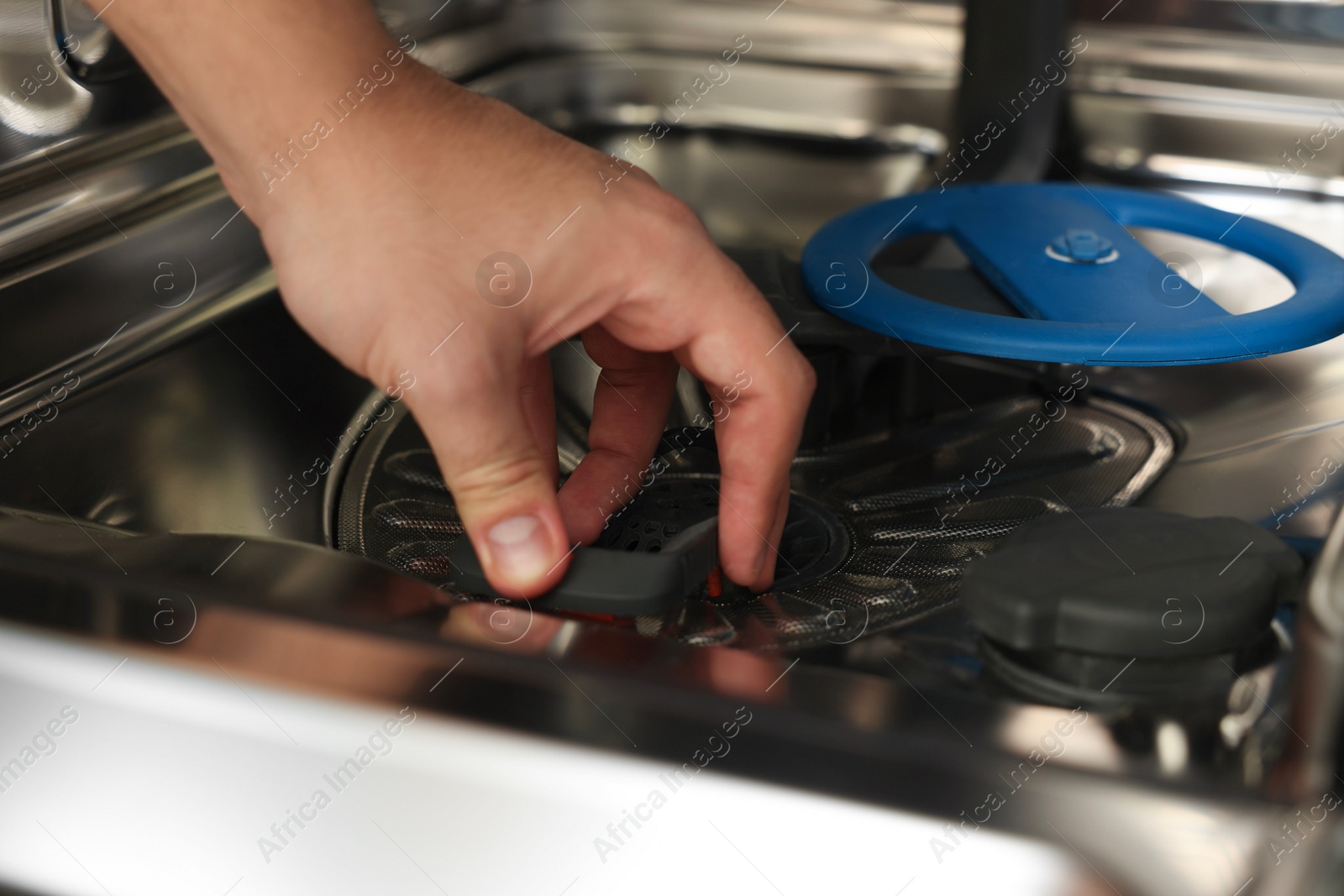 Photo of Serviceman repairing and examining chrome dishwasher, closeup