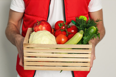 Photo of Courier with fresh products on light background, closeup. Food delivery service