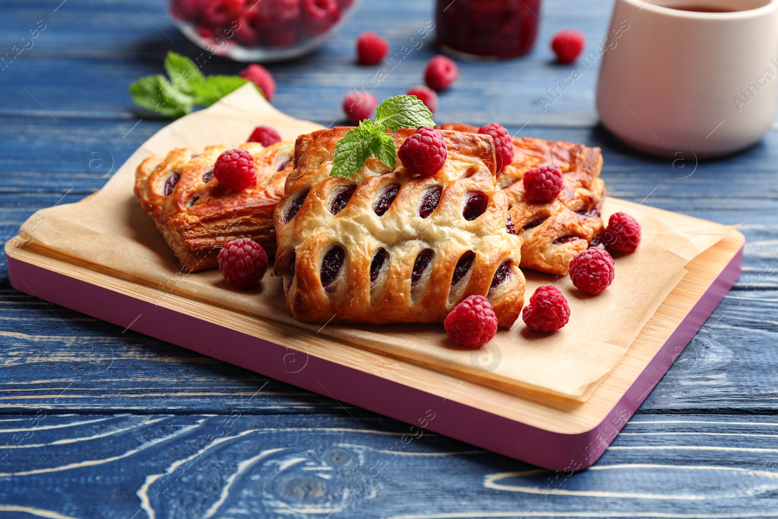 Photo of Fresh delicious puff pastry with sweet berries served on blue wooden table