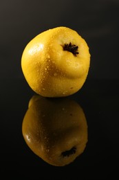 Tasty ripe quince with water drops on black mirror surface