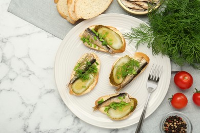 Photo of Delicious sandwiches with sprats, pickled cucumber, green onion and dill served on white marble table, flat lay. Space for text