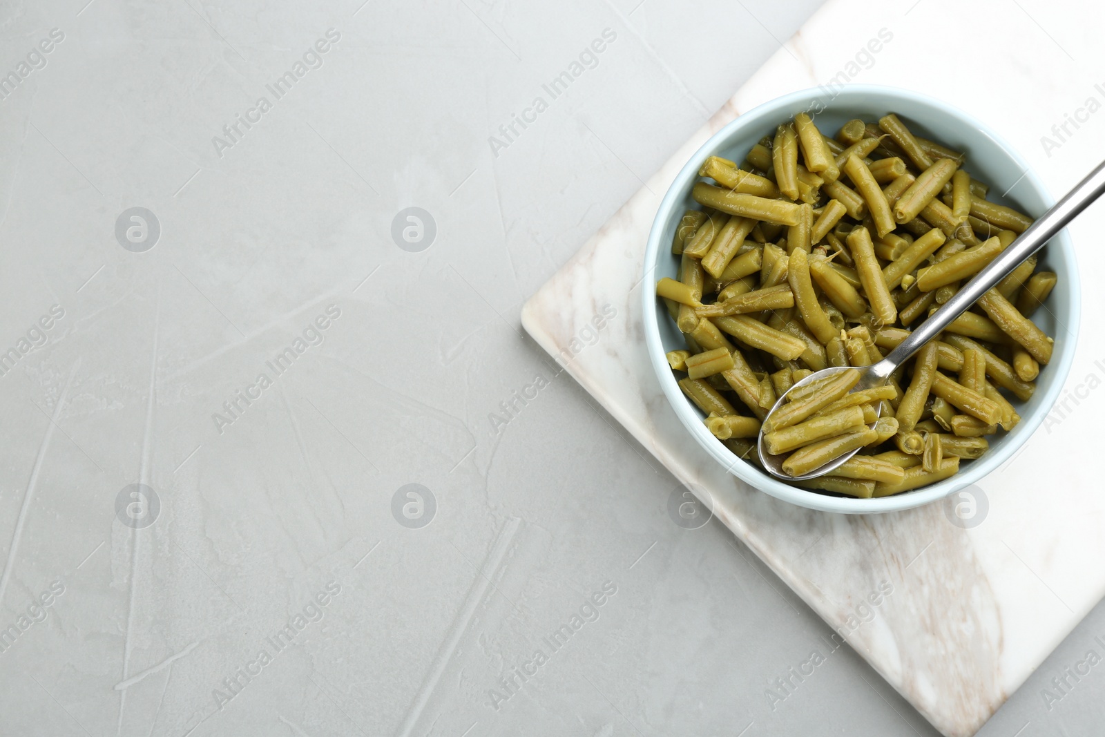 Photo of Canned green beans on light grey table, top view. Space for text