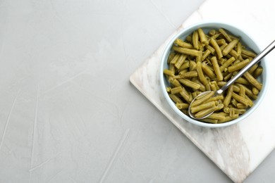 Photo of Canned green beans on light grey table, top view. Space for text