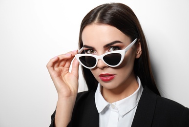 Photo of Young businesswoman in stylish sunglasses on light background